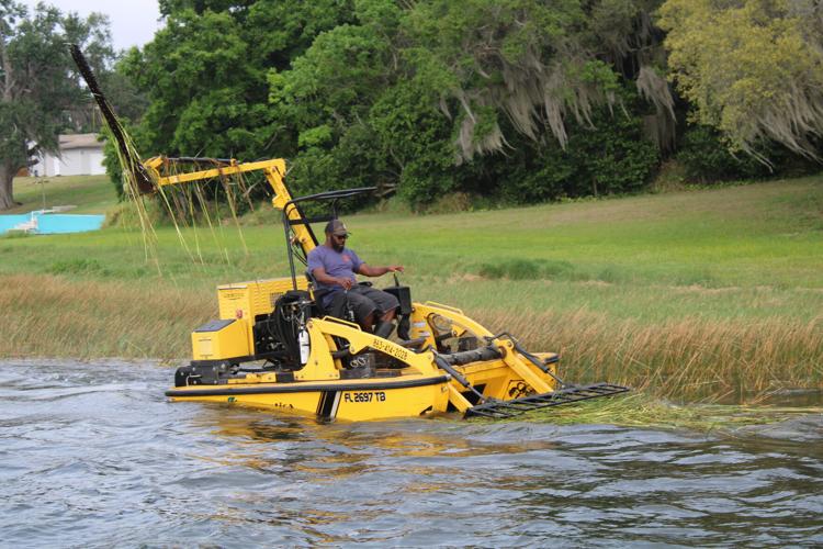 Raymond Carter scoops up the weeds he just cut with the blade on the Weedoo.